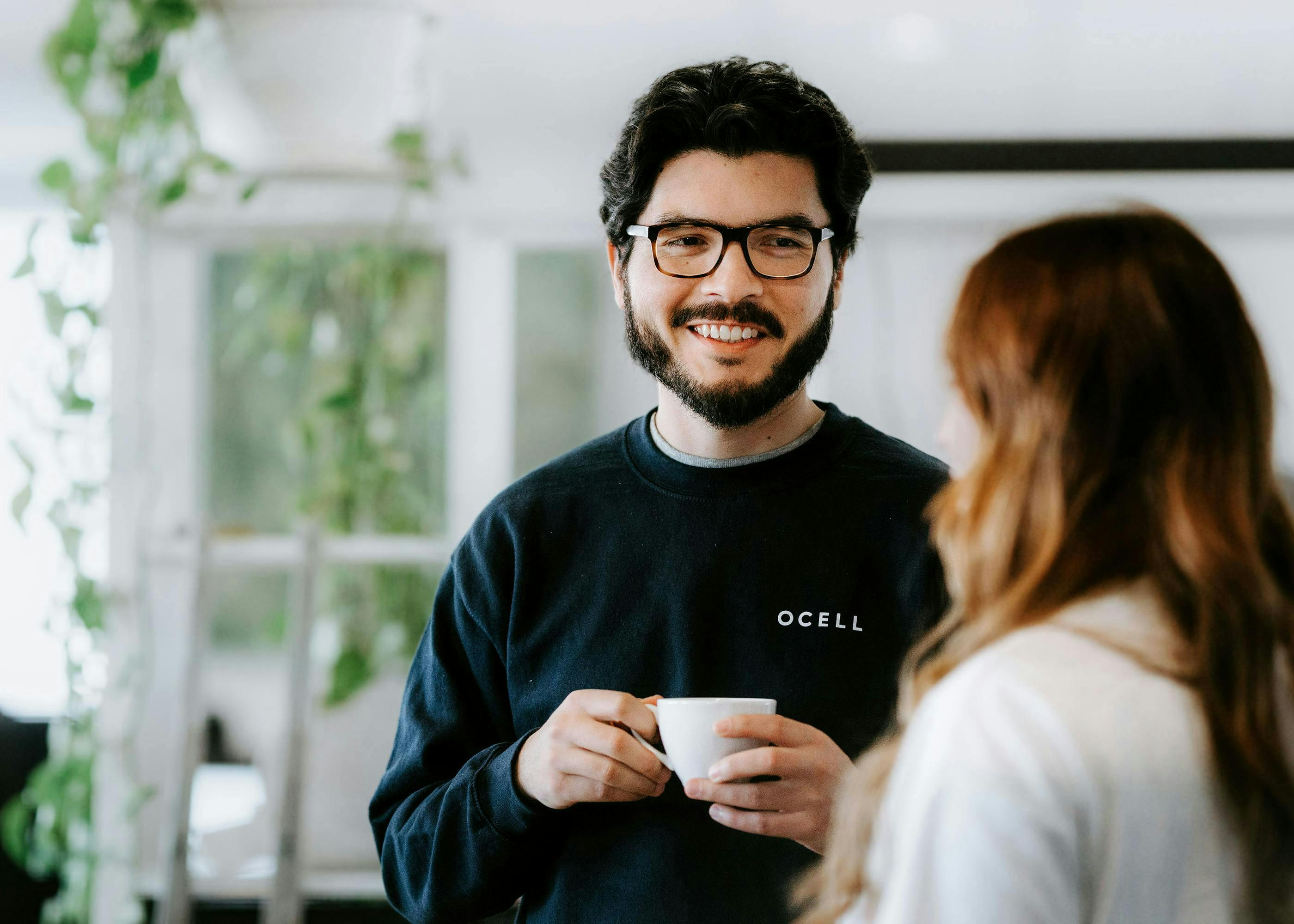 Two employees (male and female) having a coffee chat.